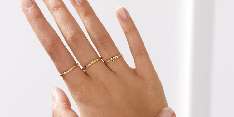 Goldene Fingerringe an drei Fingern der Hand getragen