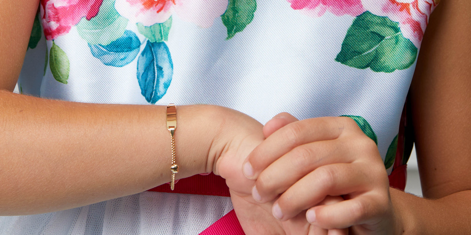Goldenes Gravurarmband mit Ring an Kinderhand, traditionelles Taufgeschenk