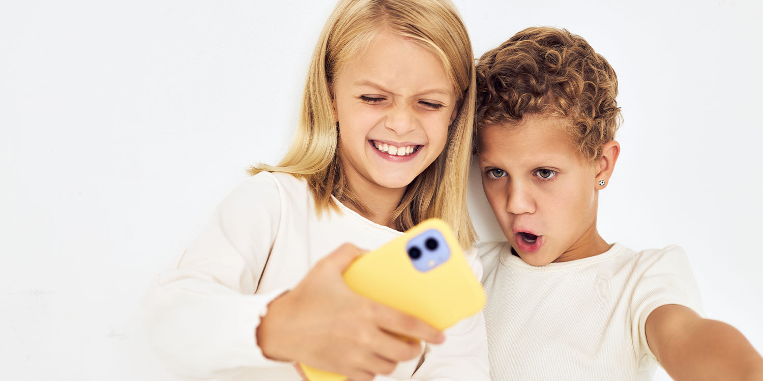 Zwei Kinder machen ein Selfie mit gelbem Handy,  beide in weißen T-Shirts