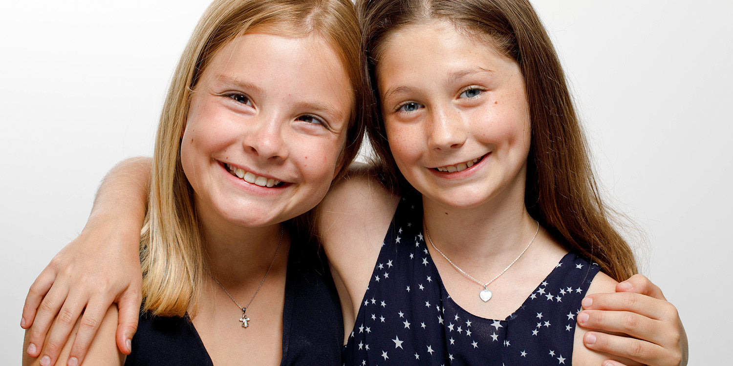 Freundinnen präsentieren silberne Kinderketten mit Stern- und Herz-Anhängern