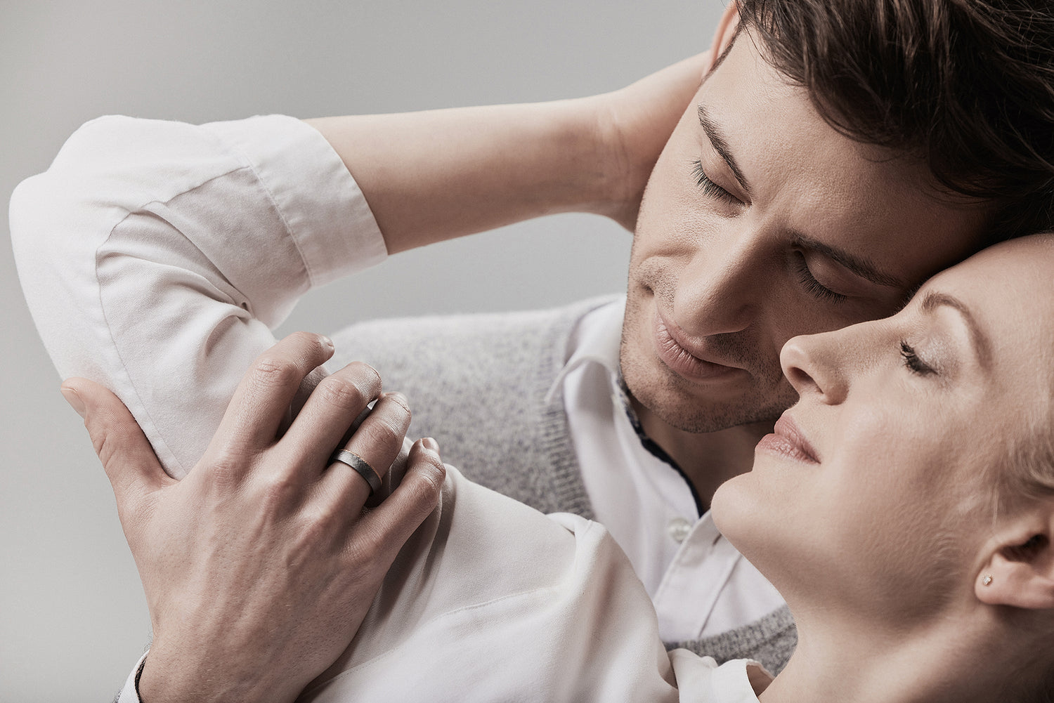 Romantisches Paar in weißer Kleidung hält Händchen - beide tragen bicolor Eheringe