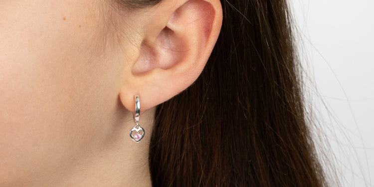 Silberne Creolen mit rosafarbenem Kristallanhänger am Ohr getragen