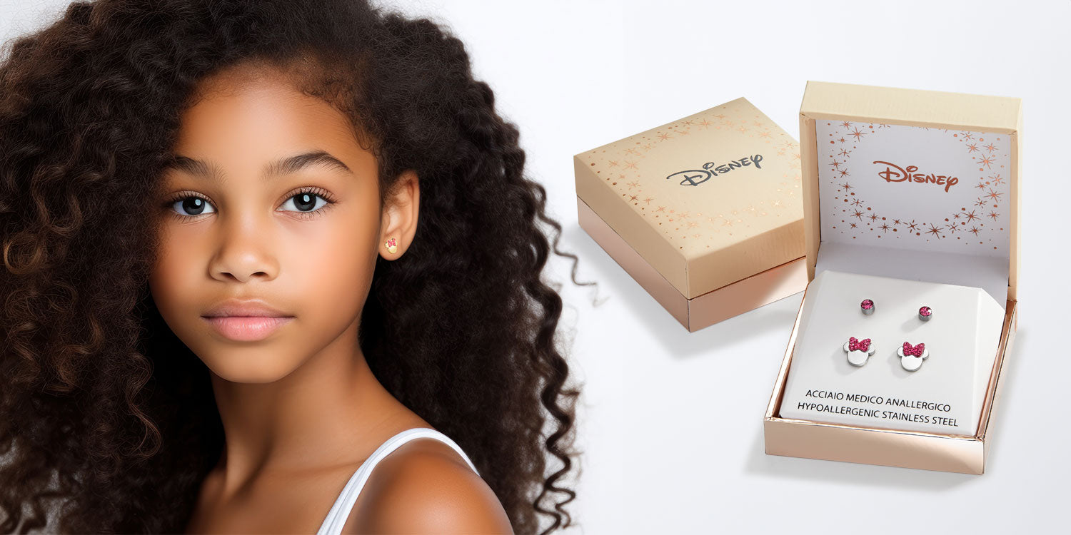 Junges Mädchen mit lockigen Haaren trägt kleine Ohrstecker, neben Disney-Schmuckschachteln mit Minnie Mouse Ohrringen in Geschenkverpackung