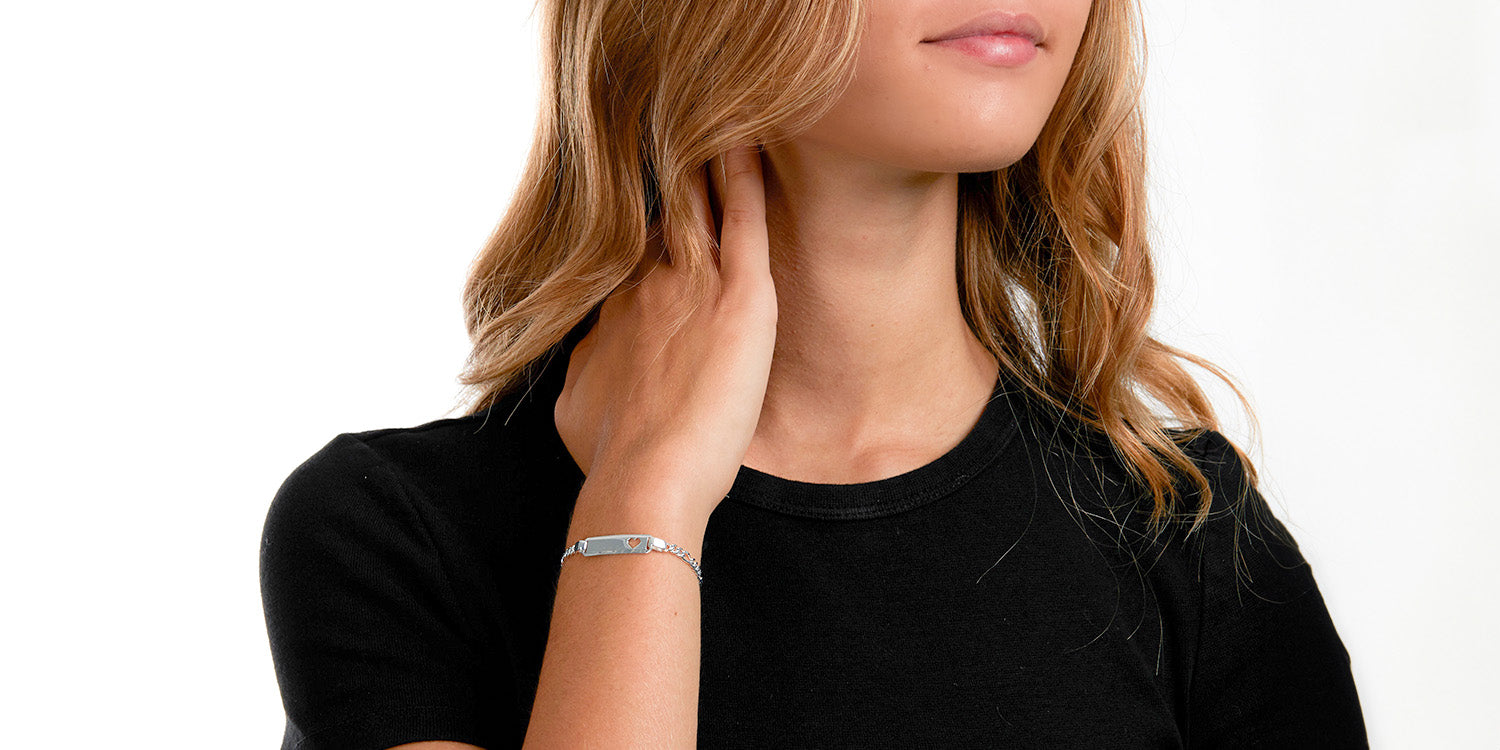 Frau in schwarzem Top trägt silbernes Gravur-Armband mit rechteckigen Gliedern am Handgelenk